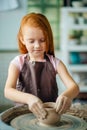 Redhead Child sculpts from clay pot. workshop on modeling on potter`s wheel. Royalty Free Stock Photo