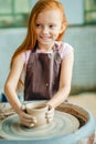 Redhead Child sculpts from clay pot. workshop on modeling on potter`s wheel. Royalty Free Stock Photo