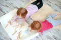 Children draw with colored pencils lying on the floor