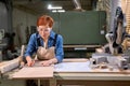 Redhead female carpenter working as wood designer in small carpentry workshop