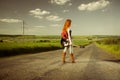 Redhead female guitarist at rural freeway