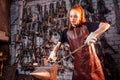 Redhead ginger woman working smithytools in dark workplace forging hammering malleation details. small business concept