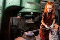 Redhead ginger woman working smithytools in dark workplace forging hammering malleation details. small business concept