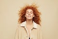 Redhead Girl. Beautiful Woman In Beige Jacket Portrait. Ginger Hair Female Standing With Closed Eyes.