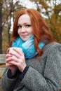 Redhead girl with cup in autumn park, yellow leaves and trees Royalty Free Stock Photo