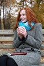 Redhead girl with cup in autumn park, yellow leaves and trees Royalty Free Stock Photo