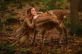 Redhead girl with deer in a long dress