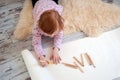 Girl draws with colored pencils, lying on the floor