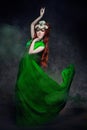 Redhead girl fabulous look, green long dress, bright makeup and big eyelashes. Mysterious fairy woman with red hair. Big eyes and Royalty Free Stock Photo