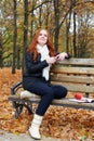 Redhead girl with headphones listen music on player in city park, fall season Royalty Free Stock Photo