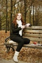 Redhead girl with headphones listen music on player in city park, fall season Royalty Free Stock Photo