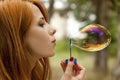 Redhead girl inflate soap bubble Royalty Free Stock Photo