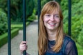 Redhead girl laughing holding metal bars of entry gate