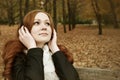 Redhead girl listen music in city park, fall season Royalty Free Stock Photo