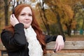 Redhead girl listen music in city park, fall season Royalty Free Stock Photo