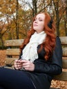 Redhead girl listen music in city park, fall season Royalty Free Stock Photo