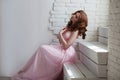 Redhead girl in pink dress sitting on the stairs Royalty Free Stock Photo