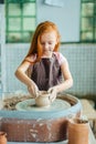 Redhead Child sculpts from clay pot. workshop on modeling on potter`s wheel. Royalty Free Stock Photo