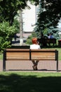 Redhead girl sitting on bench in city park and talking on phone