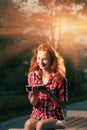 Redhead girl sitting in city park and having fun communicate via tablet PC Royalty Free Stock Photo