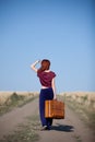 Redhead girl with suitcase at countryside road Royalty Free Stock Photo