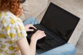 The redhead girl using a laptop. Back view. Work at home. Royalty Free Stock Photo