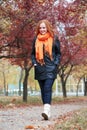 Redhead girl walk on pathway in city park, fall season Royalty Free Stock Photo