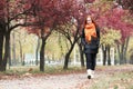 Redhead girl walk on pathway in city park, fall season Royalty Free Stock Photo