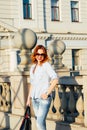 Redhead girl walking in the city. She is smiling and carefree. Casual style