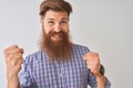 Redhead irish man listening to music using wireless earphones over isolated white background very happy and excited doing winner Royalty Free Stock Photo