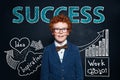 Redhead little boy in glasses and suit against hand drawing sketch and success text. Business idea and success concept Royalty Free Stock Photo