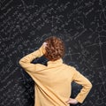 Redhead little boy thinking and looking at blackboard background with science formulas Royalty Free Stock Photo