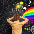 Redhead little boy thinking and standing near blackboard with many question marks, lightbulb, science and arts pattern