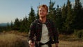 Redhead man hiking on mountain road. Joyful guy having adventure in mountains