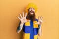 Redhead man with long beard football hooligan cheering game wearing funny wig afraid and terrified with fear expression stop