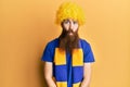 Redhead man with long beard football hooligan cheering game wearing funny wig making fish face with lips, crazy and comical Royalty Free Stock Photo
