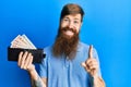 Redhead man with long beard holding wallet united kingdom pounds smiling with an idea or question pointing finger with happy face,