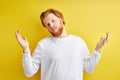 Handsome redhead caucasian man wearing casual sweater over isolated yellow background clueless and confused Royalty Free Stock Photo