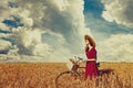 Peasant girl with bicycle on wheat field.