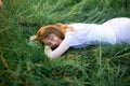 Redhead portrait of a beautiful young sexy red-haired woman, lying in the spring sun, relaxing on the green grass. Royalty Free Stock Photo