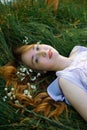 Redhead portrait of a beautiful young sexy red-haired woman, lying in the spring sun, relaxing on the green grass. Royalty Free Stock Photo