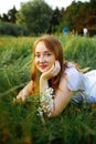 Redhead portrait of a beautiful young sexy red-haired woman, lying in the spring sun, relaxing on the green grass. Royalty Free Stock Photo