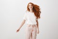 Redhead rule world. Portrait of carefree happy and charming female with ginger hair, jumping joyfully over gray Royalty Free Stock Photo