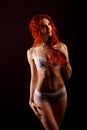 Redhead sexy cabaret dancer in lingerie on a dark background, free space for your text Royalty Free Stock Photo