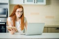 Redhead using the tablet pc and laptop in kitchen Royalty Free Stock Photo