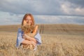 Redhead woman with bakery products in ripe wheat field