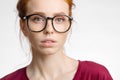 Redhead woman in glasses with hair knot looking at camera on white background Royalty Free Stock Photo