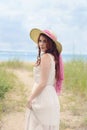 Redhead woman with hat on beach path