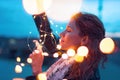 Redhead woman holding fairy light garland at evening and dreaming closeup