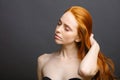 Redhead woman holding her healthy and shiny hair, studio grey Royalty Free Stock Photo